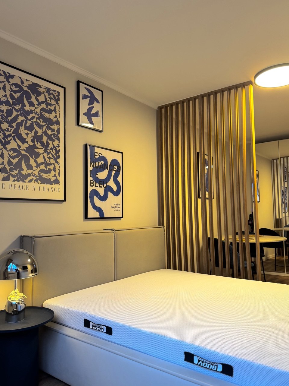 Schlafzimmer mit Holzlamellen-Trennwand und dekorativen Postern